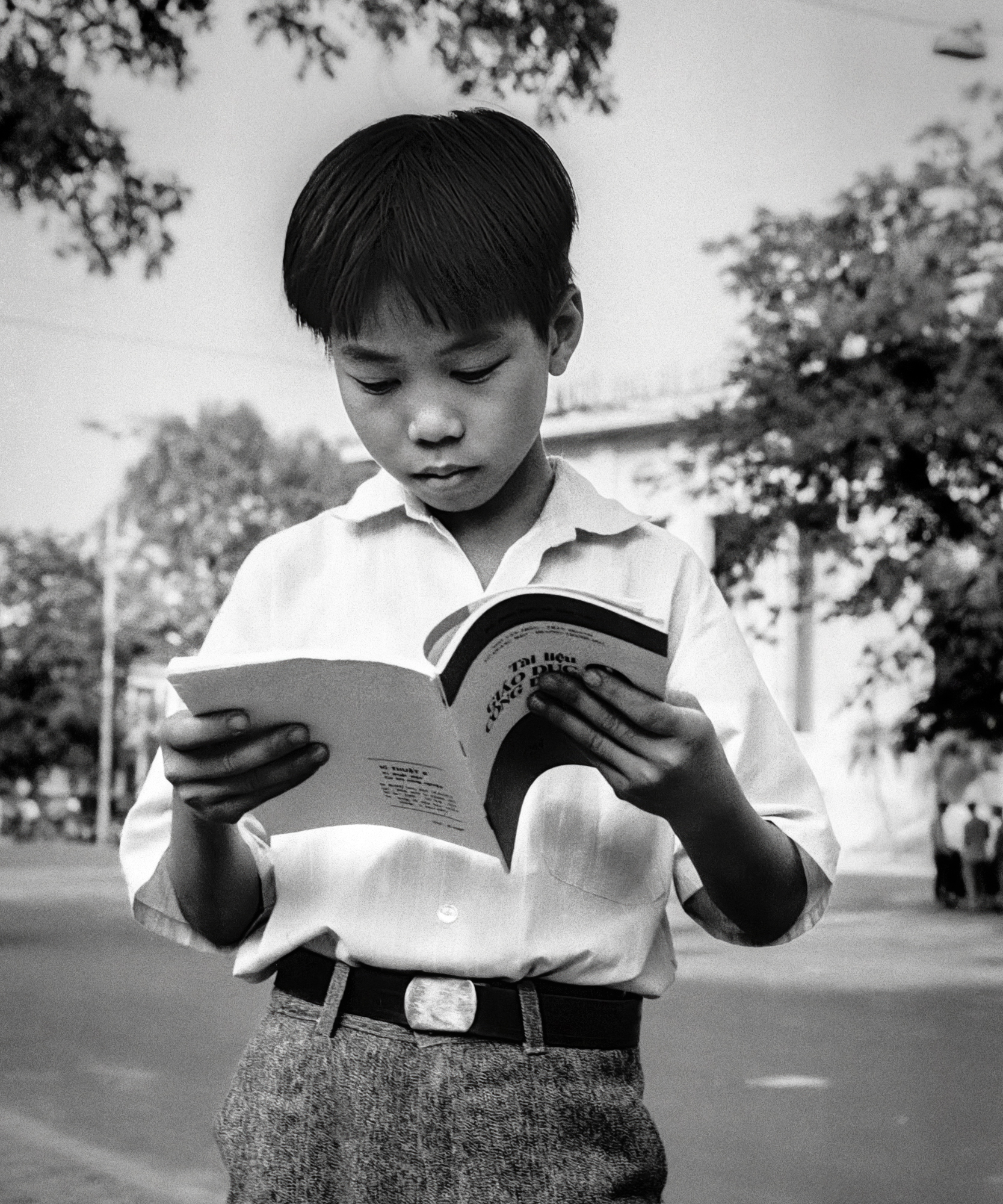 Young boy studying on the street, Hanoi, Vietnam, 1992 / Cậu bé học bài trên đường phố, 1992